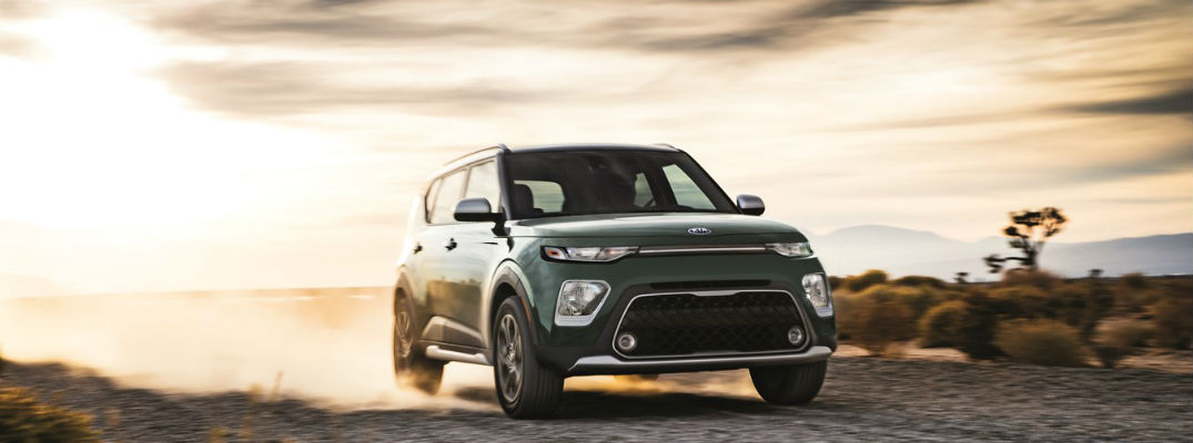 Green 2021 Kia Soul driving through dust