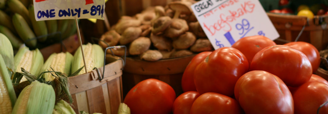 tomatoes corn and mushrooms at farmers market with signs
