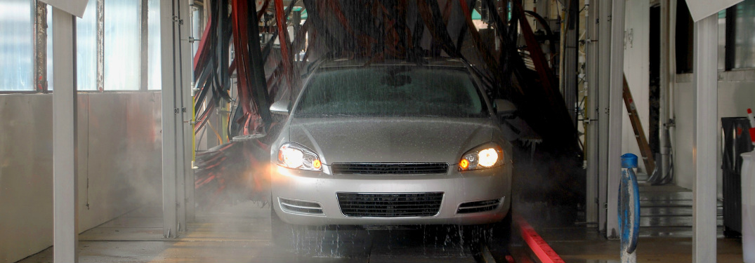 Grey sedan traveling through a car wash