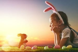 Girl wearing bunny ears sitting by a bunny