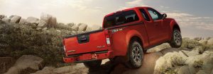 Red 2018 Nissan Frontier driving up hill off-road