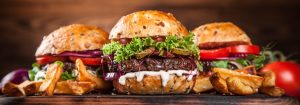 Three burgers on a slab of wood