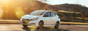 white Nissan Leaf driving down road