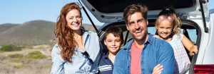 family smiling at the back of their vehicle