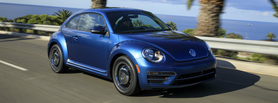 2018 Volkswagen Beetle blue driving down road in tropical location by ocean and palm trees
