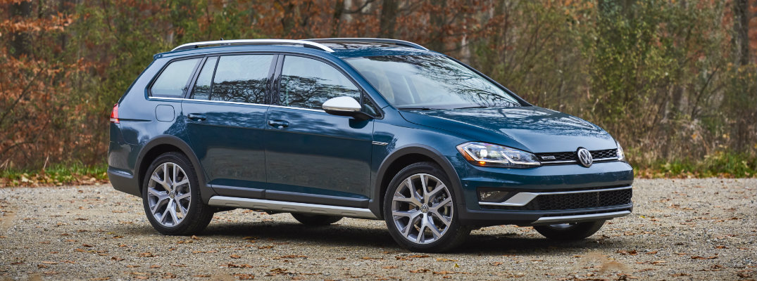 2018 Volkswagen Golf Alltrack Silk Blue Metallic paint color exterior shot parked on a dirt gravel parking lot within a fall forest with falling leaves