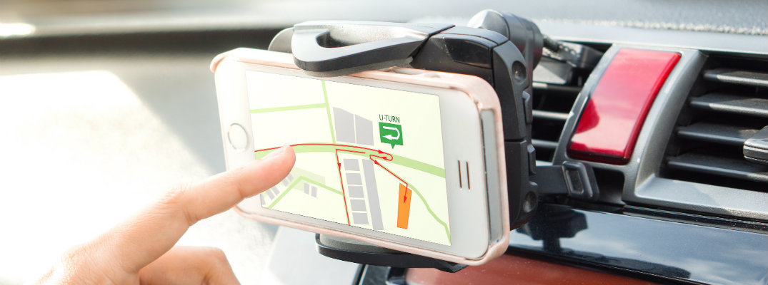 Finger touching smartphone GPS system mounted in used vehicle