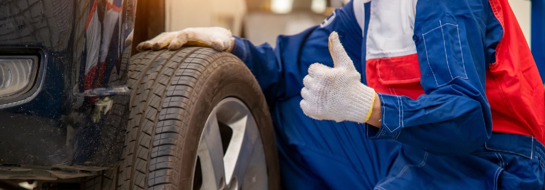 Mechanic with thumbs up next to tire
