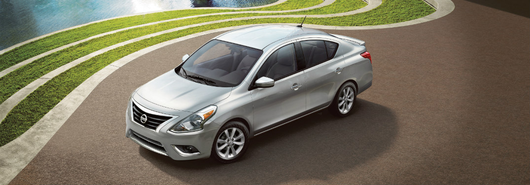 silver 2018 nissan versa parked next to grass and water