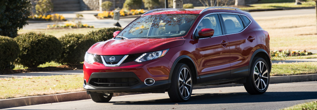 red 2018 nissan rogue sport driving on suburban road