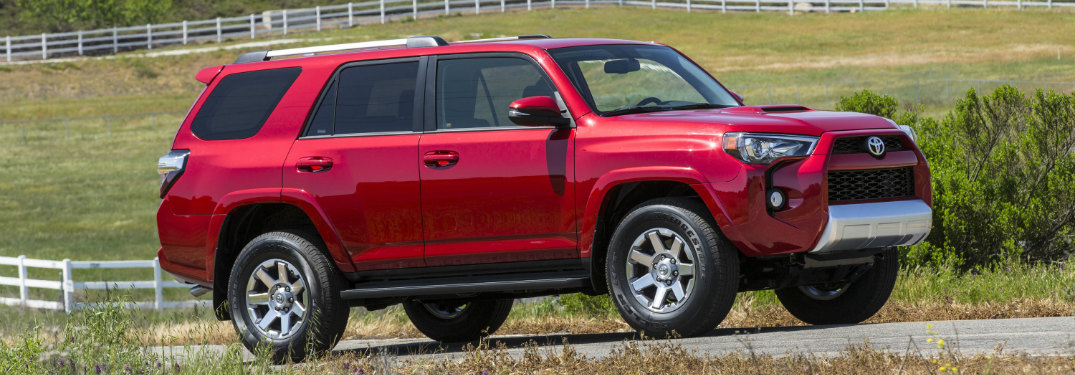 red 2018 toyota 4runner driving on farm road