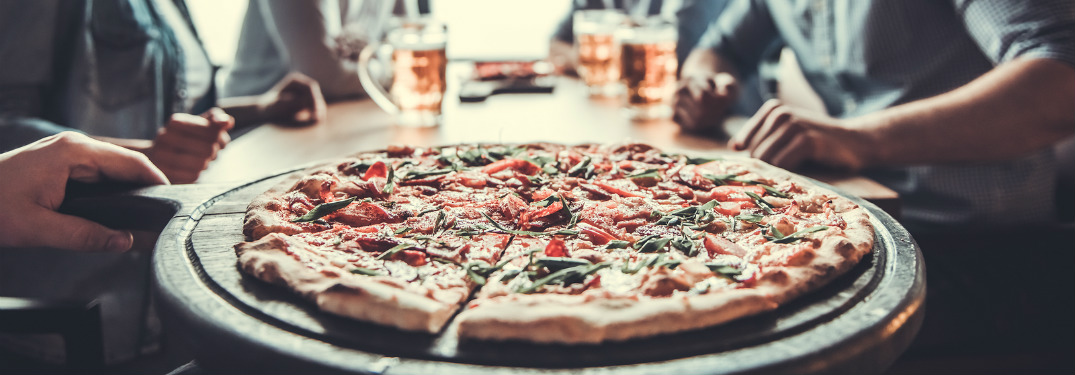 fresh pizza on plate being served to group of people on table