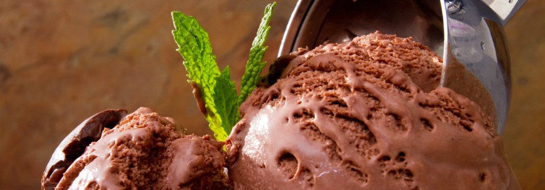 ice cream scooper scooping chocolate ice cream with mint leaf