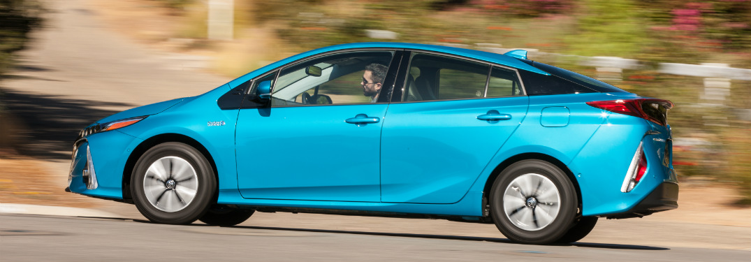 side view of blue 2018 toyota prius prime driving on road