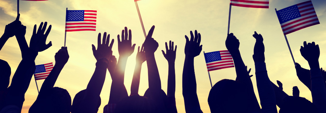 silhouettes of people with arms raised holding american flags and cheering