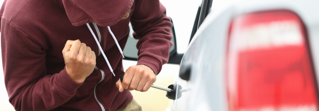 man in red hoodie trying to break into car door