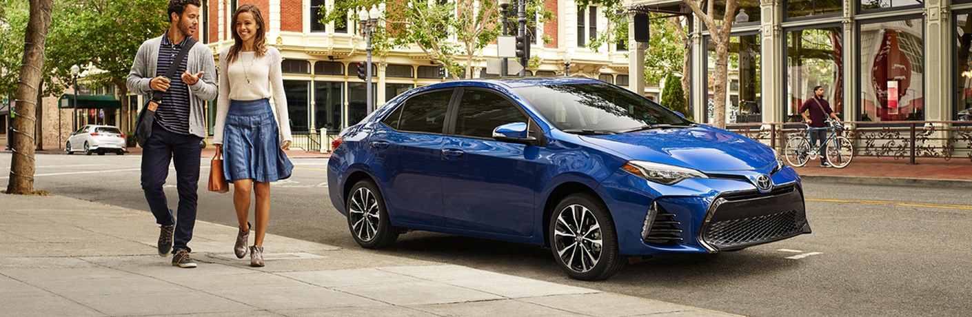 Blue 2018 Toyota Corolla parked with people observing it