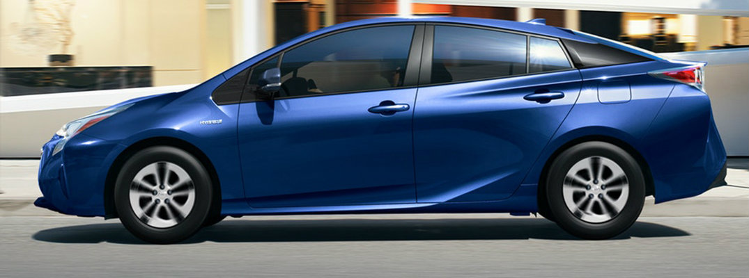 Action shot of blue 2018 Toyota Prius driving on city road in front of buildings