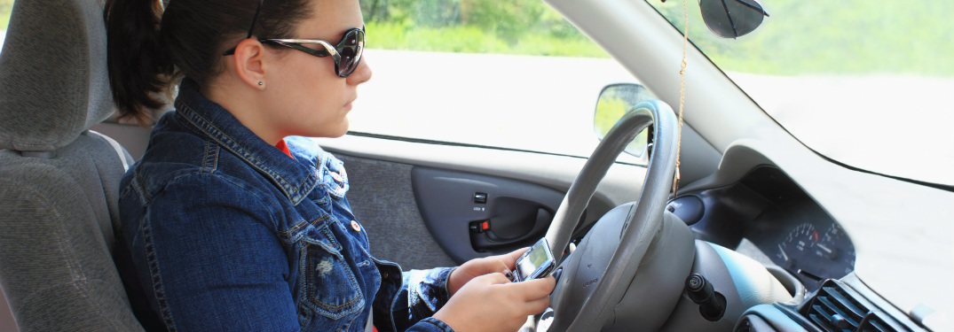 young driver checking phone while driving
