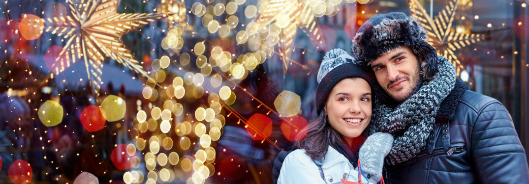 couple in winter attire outside of store full of Christmas decorations