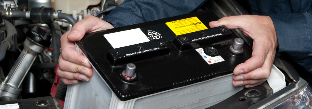 mechanic putting new battery into car