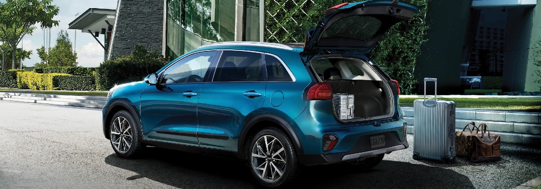 blue 2021 Kia Niro parked outside building tailgate open suitcase on ground