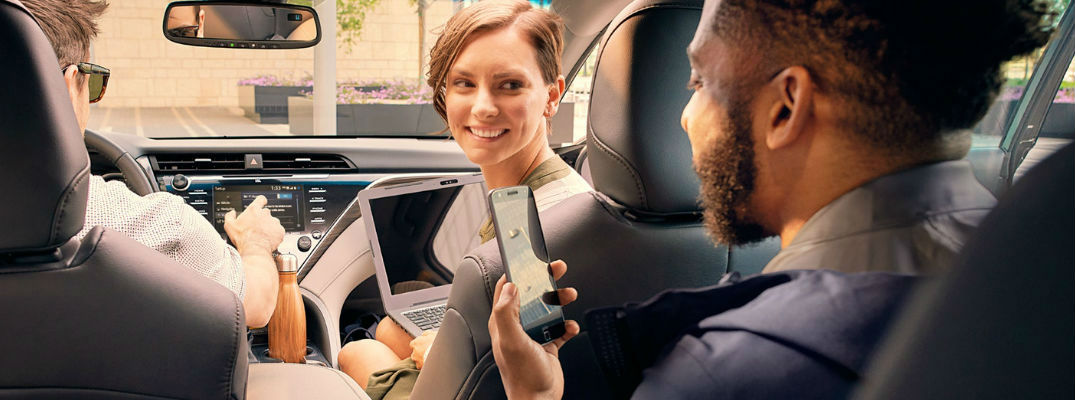 Men and Women Inside a 2018 Toyota Camry Connecting Laptop and Smartphone to Toyota Entune 3.0 Wi-Fi