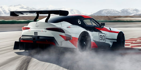 Red, White and Black Toyota GR Supra Concept Rear Exterior Drifting on a Track with Mountains in the Background