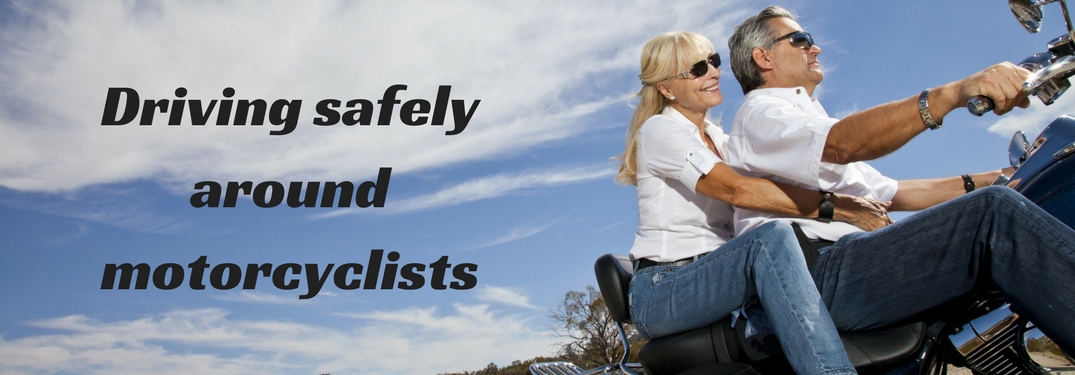 Driving safely around motorcycles text overlaid on image of two people riding on a motorcycle