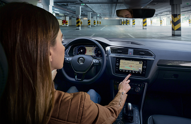 Woman fiddles with the navigation screen inside a 2020 Volkswagen Tiguan
