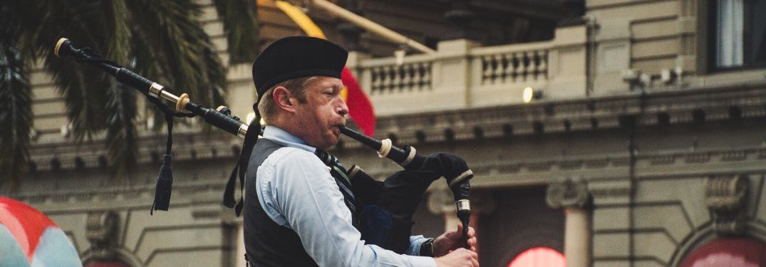 A man blows a bagpipe with all his might.