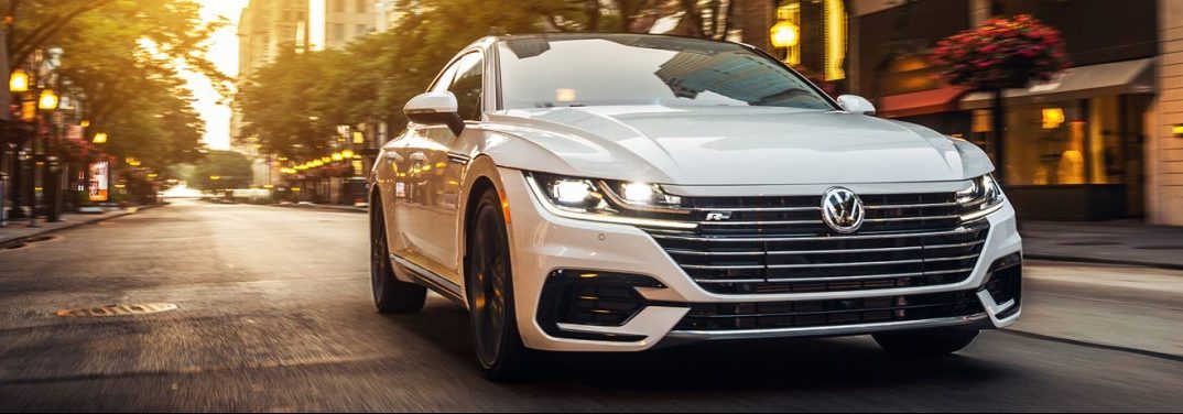 White 2020 Volkswagen Arteon cruises up a city street.