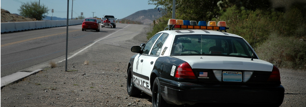 A police car waits and watches by the side of a highway