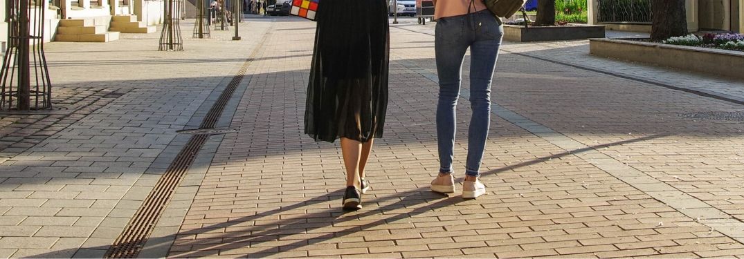 Two people walk on a city cobblestone path