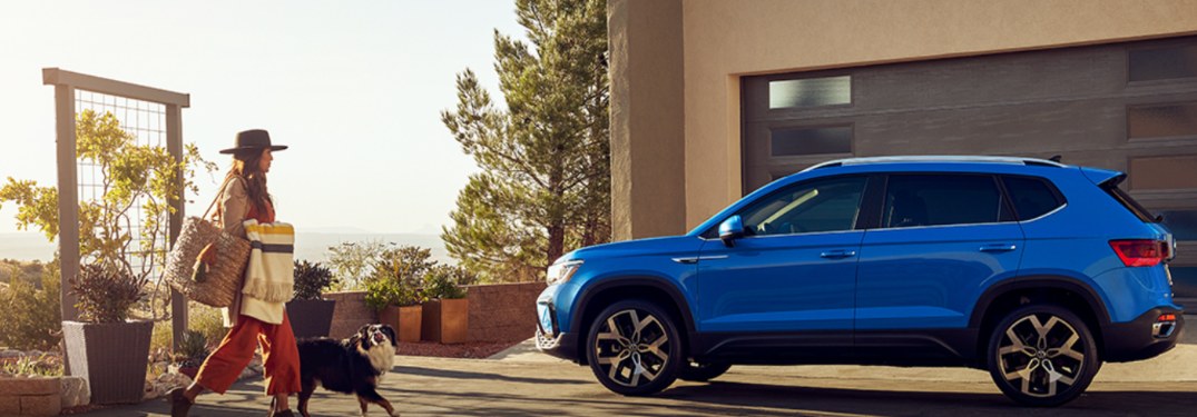 A woman and dog walking towards a 2021 Volkswagen Taos