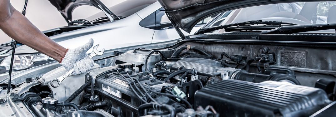 A car mechanic fixing the issues under the bonnet.