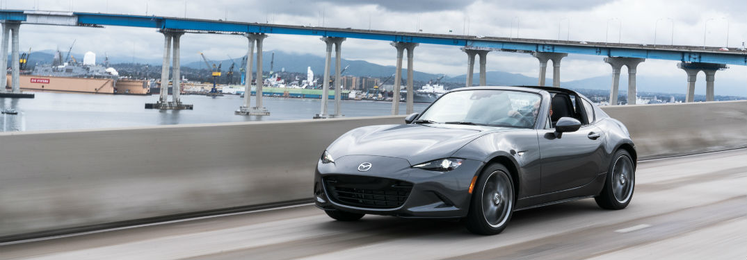 2019 Mazda MX-5 Miata RF Pricing Details with image of a Mazda Miata driving on a large bridge