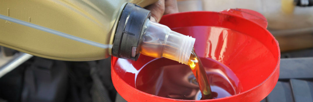 pouring oil into a car with a red funnel