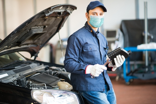 masked mechanic doing oil change