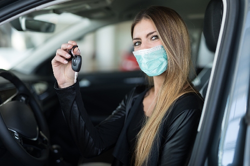 masked woman holding keys to new cars