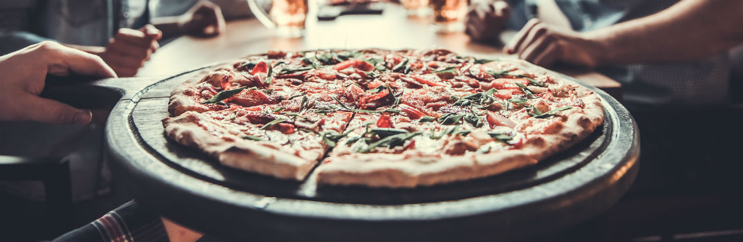 large pizza laying on a pizza platter in a pizzeria