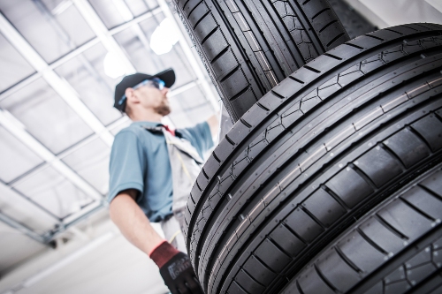 mechanic standing by a stack of new tires