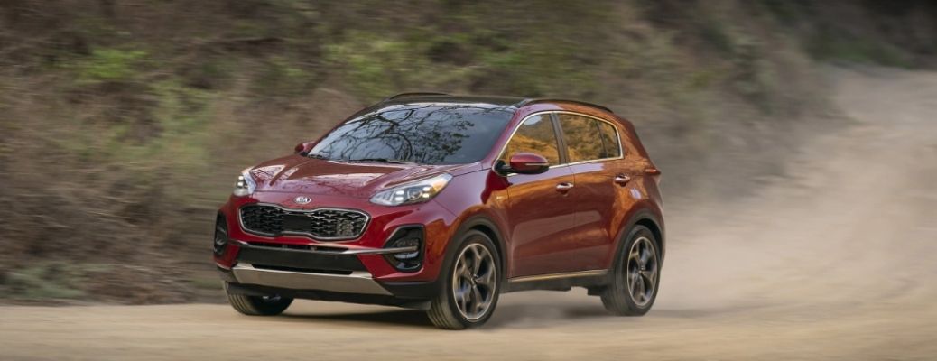 Sideview of a 2022 Kia Sportage cruising down a dusty road.
