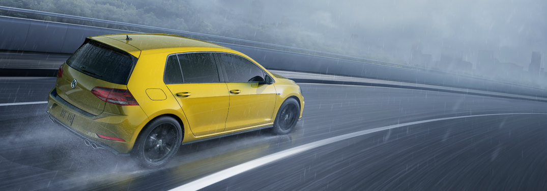 2019 VW Golf R in Ginster Yellow driving on an empty highway on a dark and stormy day