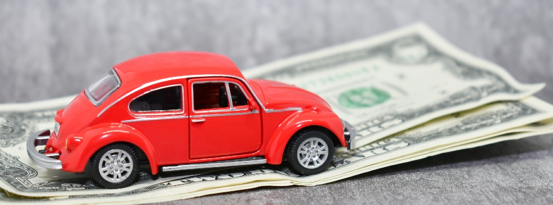 A stock photo of a toy VW Beetle on a few dollar bills.
