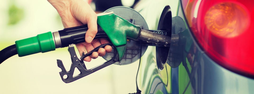 A stock photo of a person filling their car up with gas.