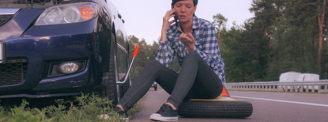 Woman on phone sitting on flat tire