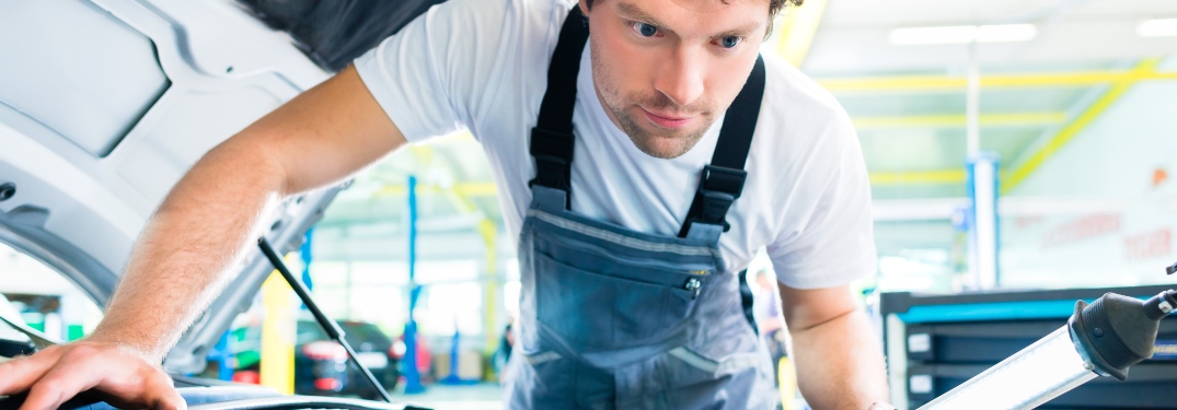 man looking under the hood of a car