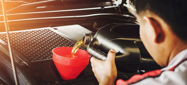 Tech pouring oil into an engine