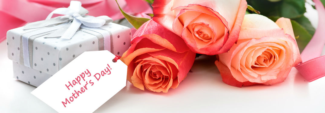 three orange roses with happy Mothers Day tag and small wrapped giftbox next to it